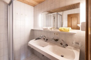 Un bagno con due lavandini, una doccia e uno specchio.