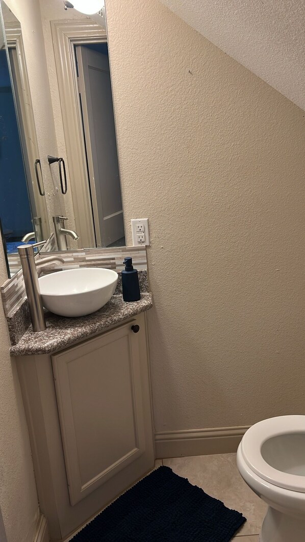 A bathroom with a white sink, a mirror, a towel rack, and a toilet.