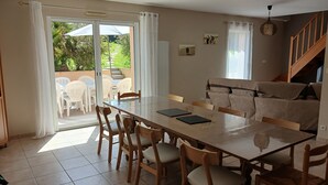 Un espace repas comprenant une table et des chaises, un canapé et un escalier.