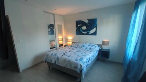 Une chambre à coucher avec un lit, des lampes de chevet, un miroir et une œuvre d’art murale.