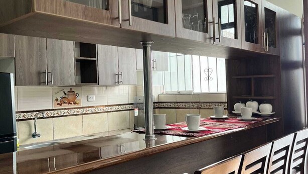 Une cuisine dotée de meubles en bois, d’un évier en acier inoxydable et d’un coin bar avec des tabourets.