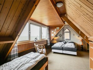 Eine Hütte mit zwei Betten, einem Fenster mit Blick und einer Holzbalkendecke.