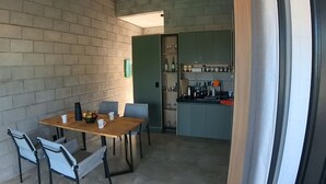 Un espace de vie compact comprenant un coin repas, une kitchenette et une grande fenêtre.