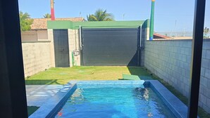 Une piscine offrant une vue dégagée sur les environs, notamment un bâtiment doté d’un toit végétalisé et un mur en briques.