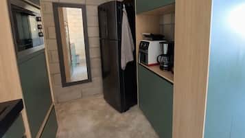 A compact kitchen with a refrigerator, a coffee maker, and a microwave.