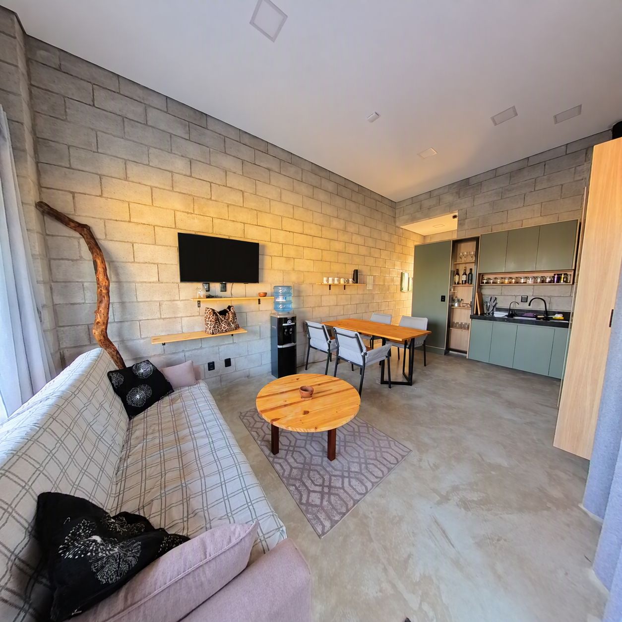 A modern living room with a sofa, coffee table, and a TV mounted on a brick wall.