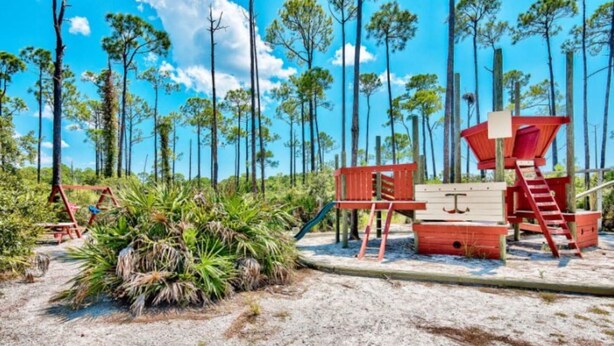 A beach playground with a slide, climbing structure, and a red and beige playhouse. - New Listing: Awesome Views Luau SanDestin Resort (Destin)