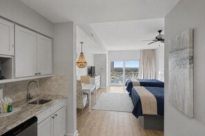 Ein modernes Hotelzimmer mit Küche, Essbereich, einem Bett mit Blick und einem Balkon.