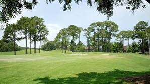 A grassy area with trees and a building in the background. - New Listing: Awesome Views Luau SanDestin Resort (Destin)