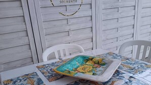 Une table recouverte d’une nappe à motifs floraux, un plateau avec de la nourriture et une chaise blanche.
