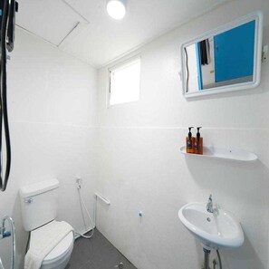 Ein kleines, weißes Badezimmer mit Toilette, Waschbecken und einem Spiegel darüber.