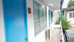 A corridor with a blue door, a window with blinds, and a tiled floor. - Trendy Double Retreat by North Pattaya's Coast (Pattaya)