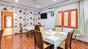 Un comedor con pared estampada, ventilador de techo y televisor.