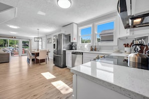 A modern kitchen with a large island, stainless steel appliances, and a view of the outdoors. - Luxury Lakefront Retreat with Private Dock ,Sleeps 16 (Lake Harmony)