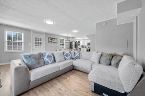 A modern living room with a sectional sofa, a kitchen in the background, and a ceiling with recessed lighting. - Luxury Lakefront Retreat with Private Dock ,Sleeps 16 (Lake Harmony)