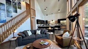 Ein großzügiger Wohnbereich mit Treppe, Sofa, Couchtisch und Sessel.