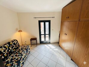 A room with a sofa, a lamp, a wardrobe, and a door.