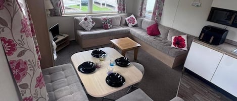 A compact living space with a sofa, a small dining table, and a kitchenette area.