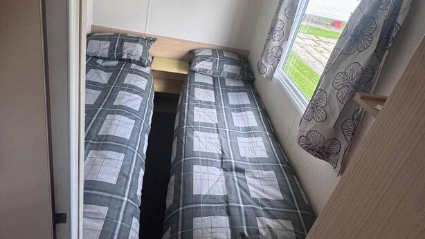 Un dormitorio pequeño con dos camas, una ventana con cortinas y una puerta.