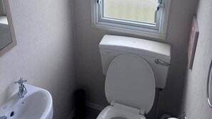 Un baño pequeño con inodoro, lavamanos y ventana.