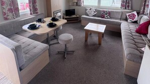 Un espacio habitable compacto con sofá, mesa de comedor y televisión.