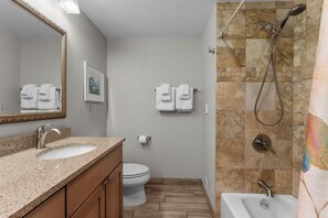 Une salle de bain équipée d’un lavabo, de toilettes, d’une douche et d’un miroir.