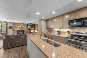 A modern kitchen with granite countertops, stainless steel appliances, and wooden cabinets. - Walk to Dillon Amphitheater and Lake at Marina Place (Dillon)