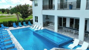 Una piscina con sillas de descanso, un comedor y vistas del paisaje circundante.