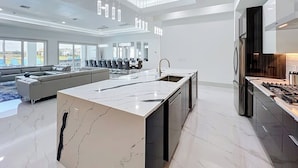 Una cocina moderna con una isla central, electrodomésticos integrados y un comedor con sofá y sillas.