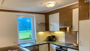 Una cocina moderna con horno empotrado, cafetera y ventana con vistas a un paisaje verde.