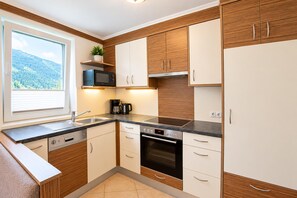 Eine moderne Küche mit Holzschränken, einer eingebauten Mikrowelle, einer Kaffeemaschine und einem Geschirrspüler.