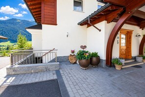 Ein Gebäude mit einer Holztreppe, einer weißen Fassade und Blick auf Berge.