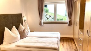 Un dormitorio con cama, armario y ventana con cortinas.
