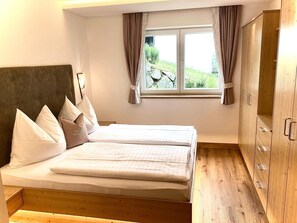 Ein Schlafzimmer mit einem Bett, einem Kleiderschrank und einem Fenster mit Vorhängen.
