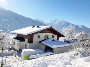 Ein schneebedecktes Chalet mit Holzdach und Bergblick.