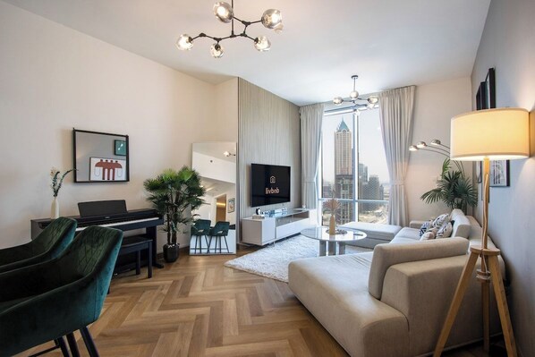 Ein modernes Wohnzimmer mit Klavier, Fernseher, Sofa und Blick auf eine Stadtlandschaft.