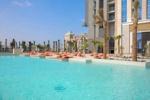 Una piscina amb gandules, palmeres i un edifici d'hotel amb cúpula i diversos pisos.