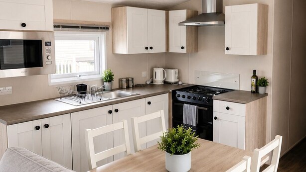 A modern kitchen with white cabinets, a microwave, stove, and a dining area with a table and chairs.