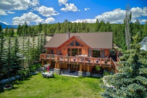 Eine Holzhütte mit Balkon, umgeben von Bäumen und einem Rasenstück.