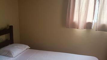 A single bed with white bedding and a folded towel.