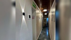 A hallway with a polished black floor, white walls, and a ceiling with recessed lighting. - Casbah Hostel (Algiers)