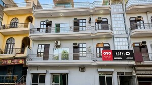 Un hôtel à plusieurs étages doté de balcons, de climatiseurs et d’une enseigne publicitaire invitant à réserver via l’application.
