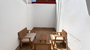 Une petite terrasse extérieure avec une table en bois et quatre chaises en bois.