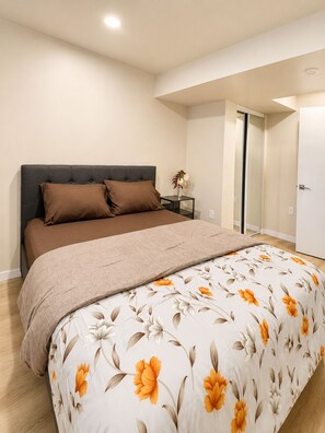 Une chambre à coucher avec un lit, une table de chevet, un vase de fleurs et une porte.