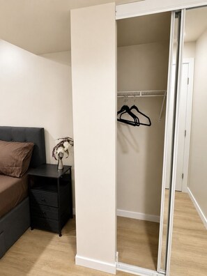 Une chambre à coucher comprenant un lit, une table de chevet, une commode, un placard avec une porte coulissante et un couloir.