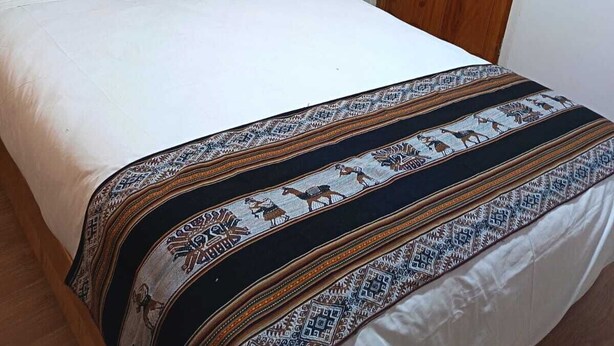 A bedroom with a bed, a wooden wardrobe, a framed picture on the wall, and a nightstand. - Omaya House: A Cozy and Quiet Room for Your Stay in Downtown Cusco (Cusco)