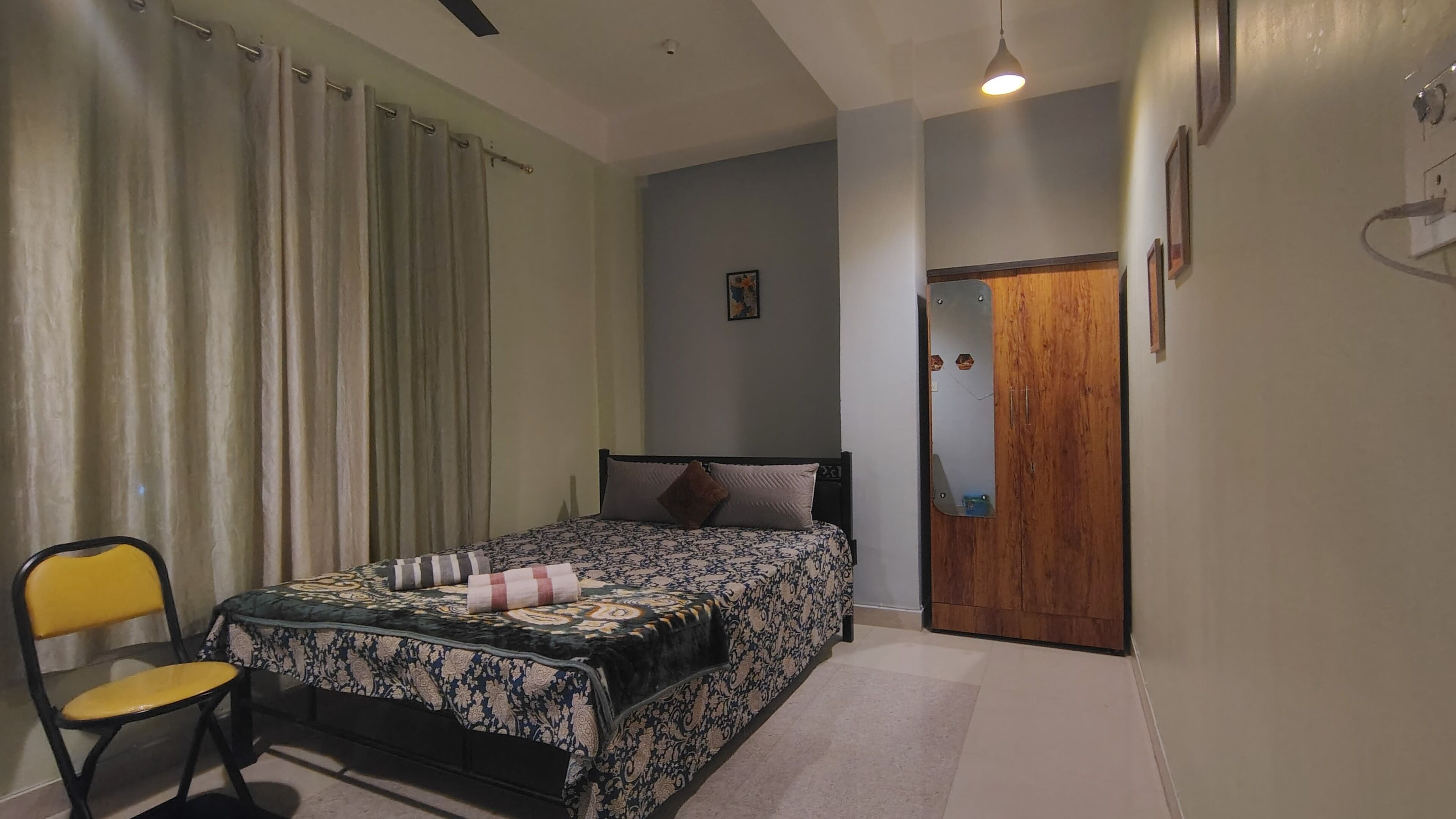 Un dormitorio con una cama, una silla, una puerta de madera y un cuadro pequeño colgado en la pared.