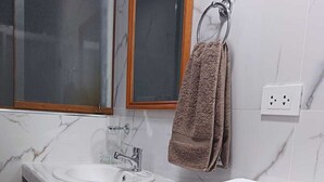 Ein Badezimmer mit Marmorwaschbecken, einem Spiegel und einem Handtuchhalter.