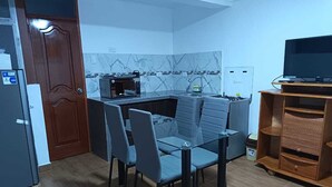 Eine kleine Küche mit Essbereich, einer Mikrowelle, einem Spülbecken und einem Fernseher auf einem Schrank.