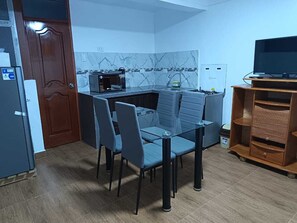 A compact kitchen with a dining area, a microwave, a sink, and a television on a stand. - Omaya House: Your Ideal Family-Friendly Mini-Apartment Retreat (Cusco)